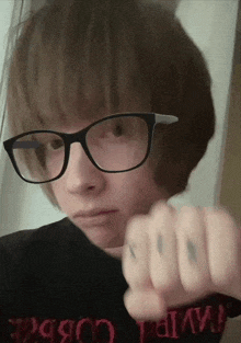 a person wearing glasses and a black shirt that says ' t.i.m.p. ' on it