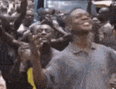 a man is standing in front of a crowd of people holding their hands up in the air .