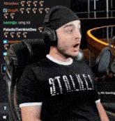 a man wearing headphones and a black shirt is sitting in a chair and making a funny face .
