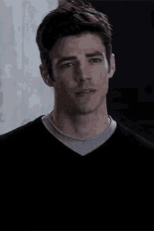 a close up of a man 's face wearing a black sweater and a grey t-shirt .