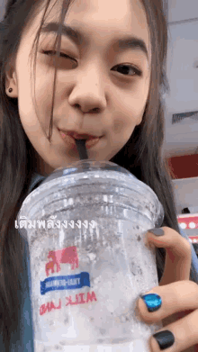 a woman is drinking from a plastic cup that says ' mai xim ' on it