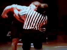 a referee in a striped shirt is standing on a basketball court during a game .