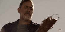 a man with a beard is holding a broken guitar in his hands .