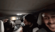 a group of men are sitting in the back of a car .