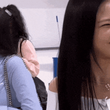 a woman with long black hair is smiling in front of a whiteboard