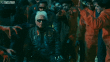 a man wearing sunglasses is surrounded by zombies with xtoms written on the bottom of the screen