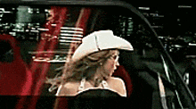 a woman wearing a white cowboy hat is sitting in a car .