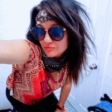 a woman wearing sunglasses and a bandana taking a selfie