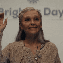 an elderly woman stands in front of a sign that says bright day