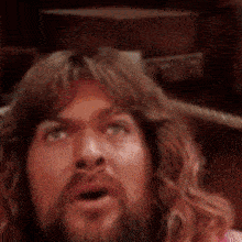 a man with long hair and a beard looks surprised with his mouth open