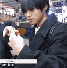 a man in a black coat is holding a piece of food in front of a sign that says 3277-2888