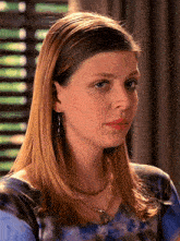 a woman wearing a blue tie dye shirt and a necklace