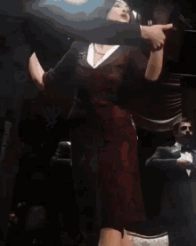 a woman in a red dress is dancing in front of a group of men in suits