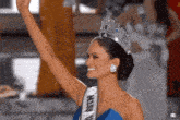 a woman wearing a blue dress and a miss u tiara