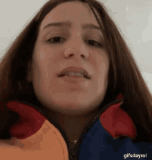a close up of a woman wearing a colorful jacket making a face .