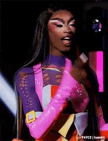 a woman wearing a purple top and pink gloves is holding a microphone in her hand .
