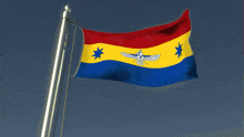 a red yellow and blue flag with a statue of a bird on it