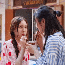 two girls drinking from a cup with straws in front of a sign that says ' strawberry '