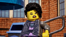 a lego girl with curly hair and a purple shirt is standing in front of a brick building