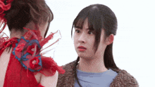two young women are standing next to each other and one of them is wearing a red dress .