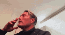 a man is smoking a cigarette in a room while looking down .
