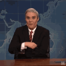 a man in a suit and tie is sitting at a desk with his fists in the air .