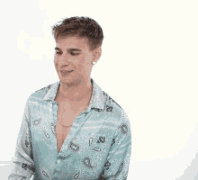 a man wearing a paisley shirt and earrings looks to the side