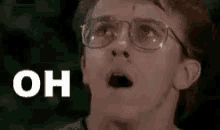 a close up of a person wearing glasses with a surprised look on their face and the word oh .