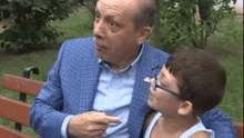 a man in a suit is talking to a young boy who is sitting on a bench