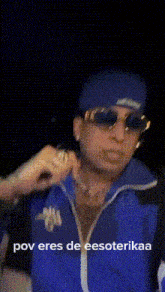 a man wearing sunglasses and a blue jacket is holding a ring .