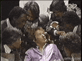 a group of people are gathered around a woman in a purple shirt
