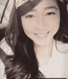 a woman is smiling while sitting in a car with a flower headband on her head .
