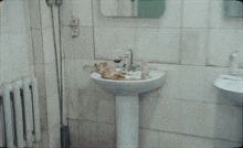 a man in a jacket is standing in a bathroom next to a sink holding a lighter .