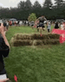 a person is taking a picture of a person jumping over hay bales in a field .