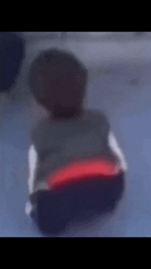 a blurry picture of a person sitting on the floor with their back to the camera .