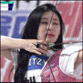 a woman is holding a bow and arrow in her hand while playing archery .