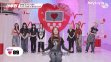 a group of young women are standing in front of a large heart .