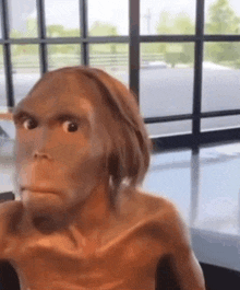 a statue of a man with a monkey face is sitting in front of a window in a room .