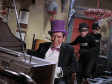 a man wearing a purple top hat is sitting in front of a tv