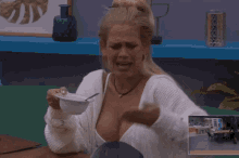 a woman is sitting at a table with a bowl of food in her hand