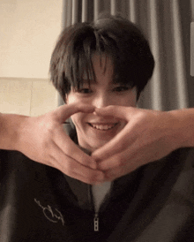 a person making a heart shape with their hands on a person 's face