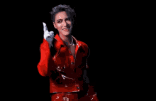 a woman wearing a red jacket and white gloves is dancing