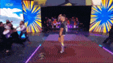 a wrestler is walking down a red carpet in front of a crowd with the aew logo on the screen behind him