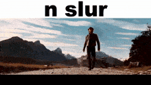 a man is walking down a dirt road with mountains in the background and the words n slur above him
