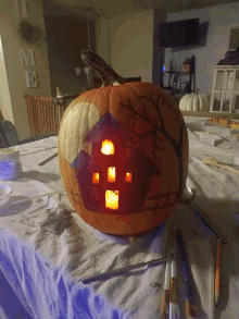 a pumpkin with a house carved into it sits on a table in front of a sign that says home