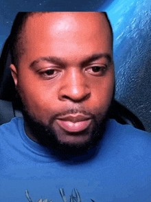 a man with a beard wearing a blue shirt is looking at the camera