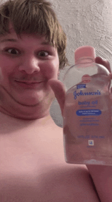 a man is holding up a bottle of johnson 's baby oil