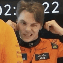 a man wearing an orange cisco shirt is making a funny face .