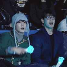 a man wearing a hat and glasses holds a light stick that says peace on it