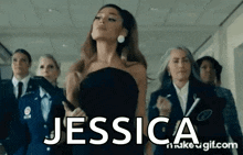 ariana grande is standing in a hallway with a group of women in suits and ties .